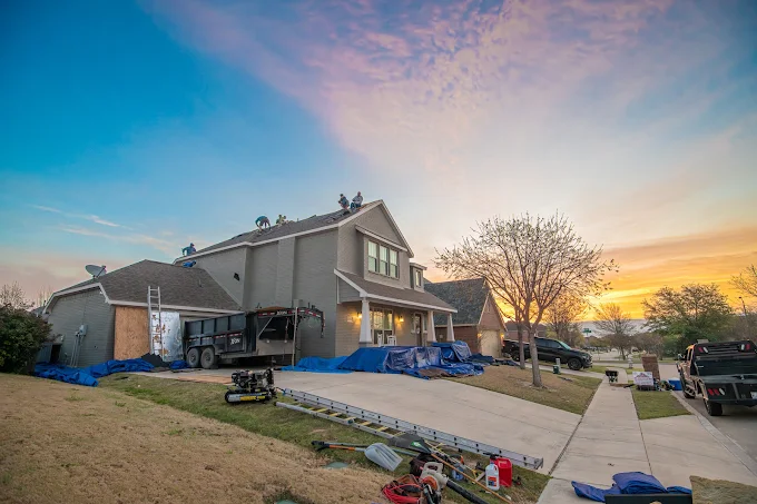 Roof replacement in progress at sunset